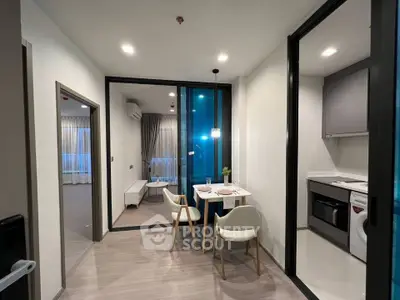 Modern apartment with open kitchen and dining area, featuring sleek design and natural lighting.