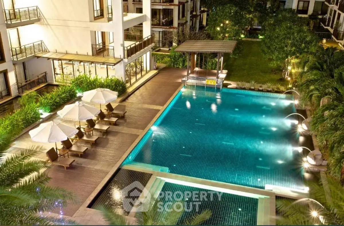 Luxurious apartment complex with stunning illuminated pool and lush garden view.
