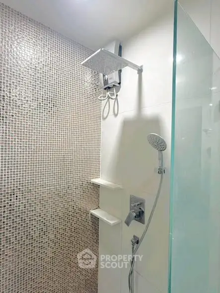 Modern bathroom with sleek shower fixtures and mosaic tile wall.