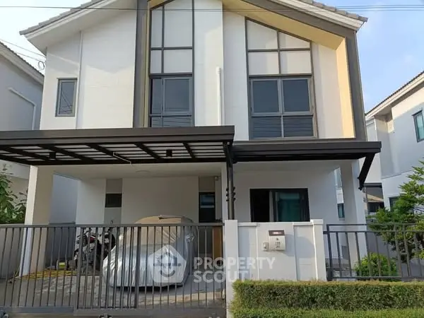 Modern two-story house with carport and gated entrance in suburban neighborhood.