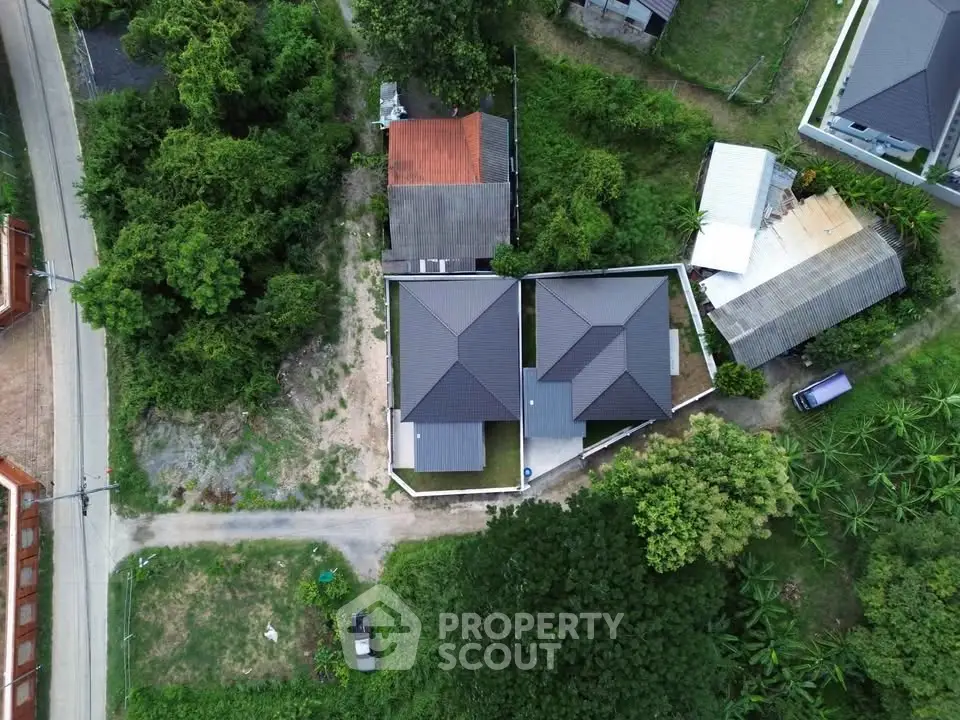 Aerial view of modern residential houses surrounded by lush greenery, showcasing contemporary architecture and serene environment.