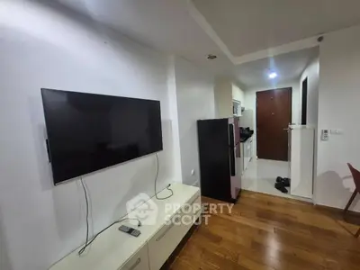 Modern apartment interior with wall-mounted TV and sleek kitchen area.