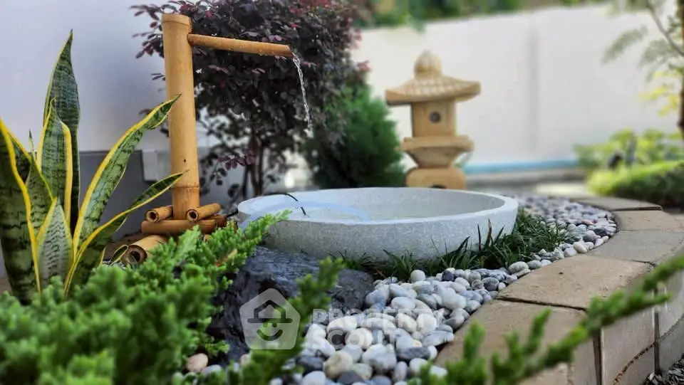 Serene garden with bamboo water feature and stone basin, perfect for tranquil outdoor living.