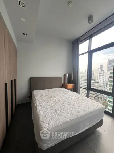 Spacious bedroom with large window offering stunning city views in modern apartment.