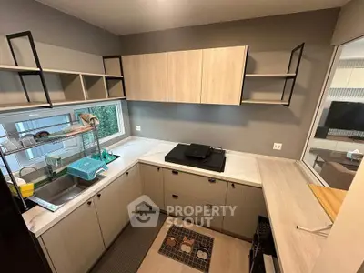 Modern kitchen with sleek cabinetry and open shelving, featuring a gas stove and ample counter space.