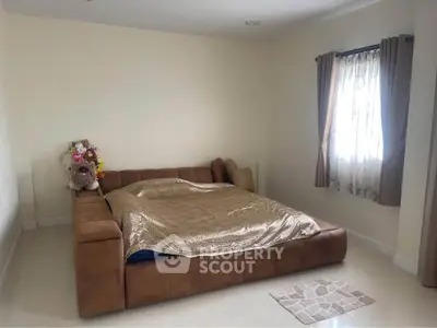 Spacious bedroom with cozy brown sofa bed and natural light from window.