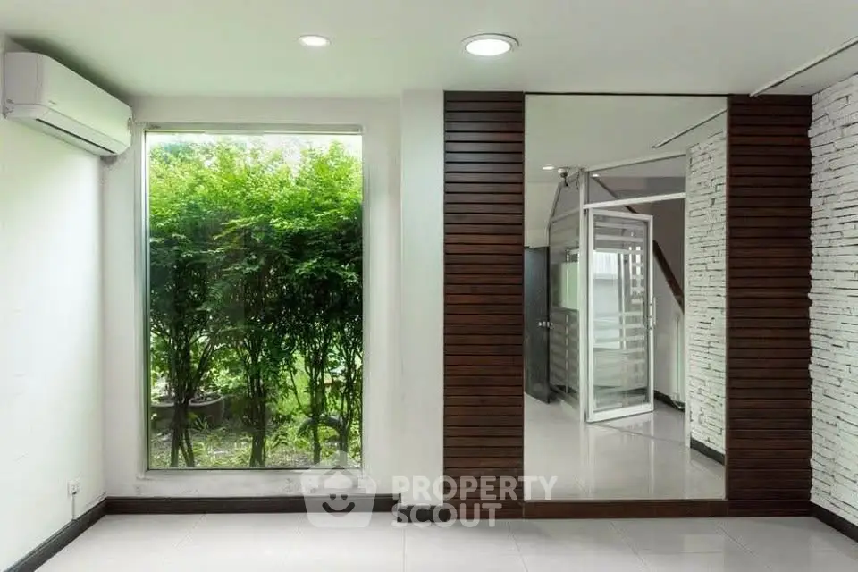 Modern interior with large window and garden view, featuring sleek wooden accents and white brick wall.