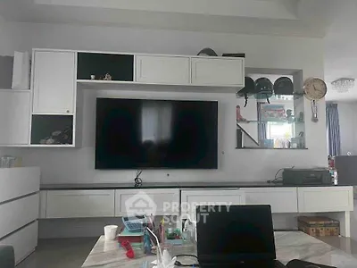 Modern living room with sleek white cabinetry and large flat-screen TV, perfect for entertainment.