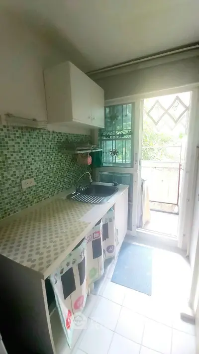 Charming kitchen with open layout and mosaic backsplash leading to a balcony.