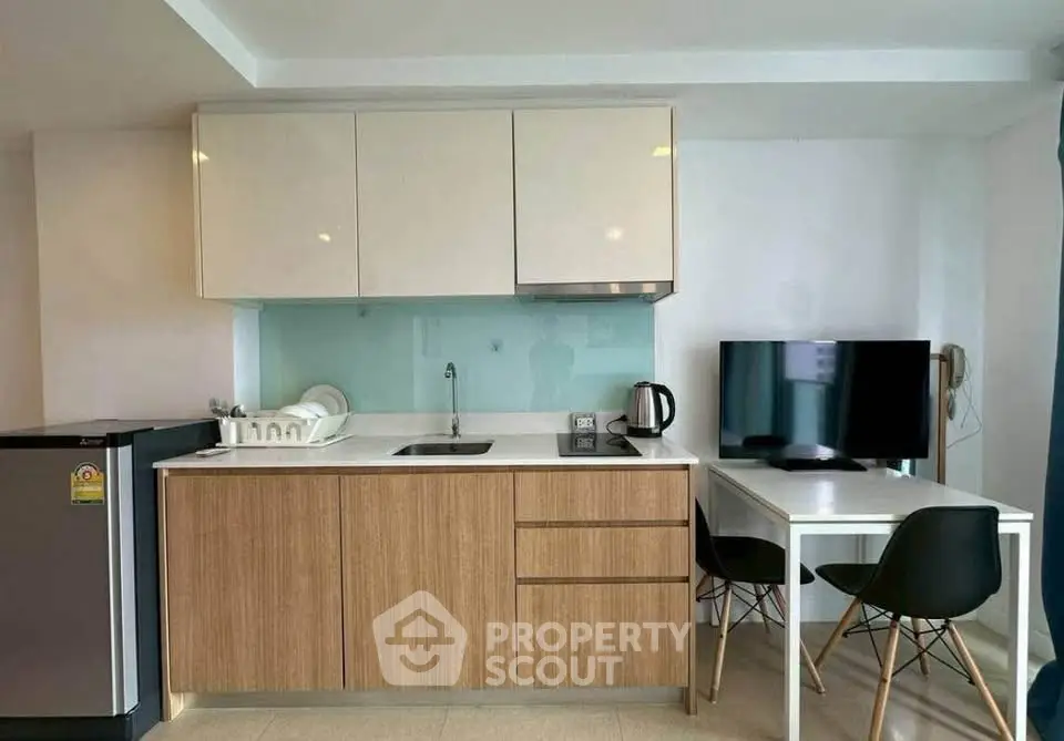 Modern compact kitchen with dining area, featuring sleek cabinetry and contemporary appliances.