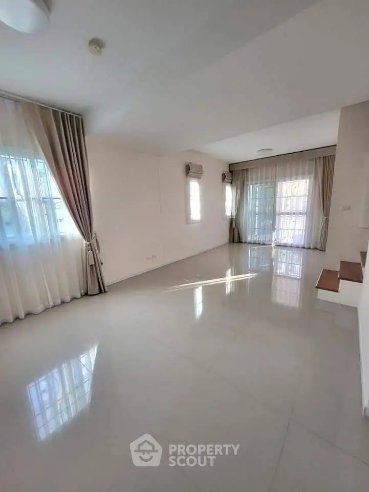 Spacious empty living room with large windows and elegant curtains