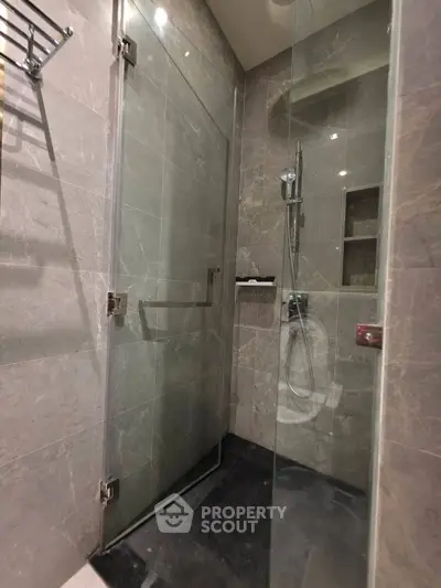 Luxurious modern bathroom with sleek glass shower enclosure and elegant marble tiles.