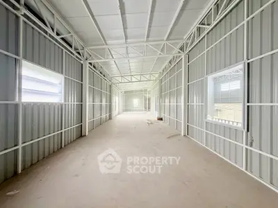 Spacious industrial warehouse interior with high ceilings and ample natural light.