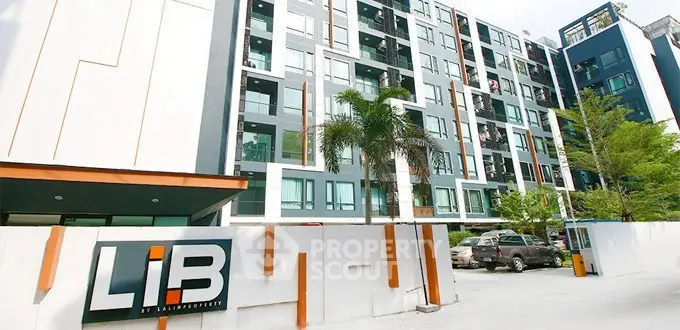 Modern apartment building with sleek design and ample parking space.