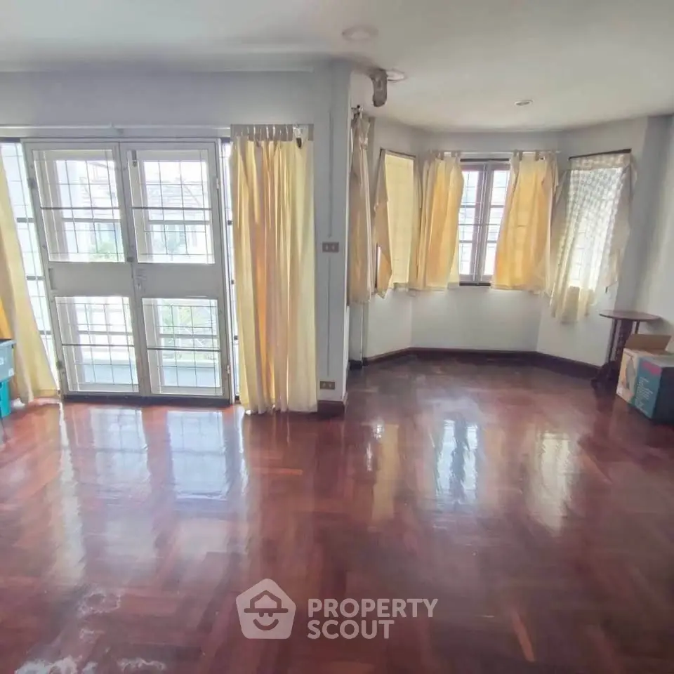 Spacious living room with wooden floors and large windows for natural light.