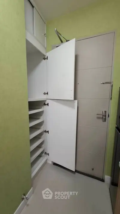 Compact storage space with white cabinets and modern door in a cozy apartment.