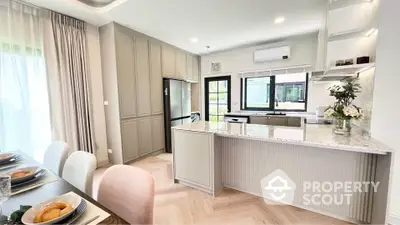 Modern kitchen with marble countertops and open layout, featuring elegant dining area and natural light.