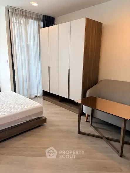 Modern bedroom with stylish furniture and natural light, featuring a cozy bed, sleek wardrobe, and elegant sofa.