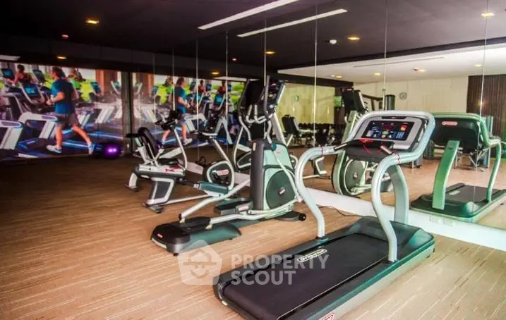 Modern gym with state-of-the-art fitness equipment and mirrored walls in luxury residential building.