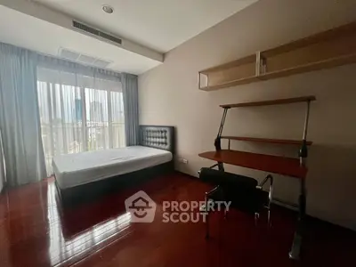 Spacious bedroom with modern furniture and large window offering natural light.