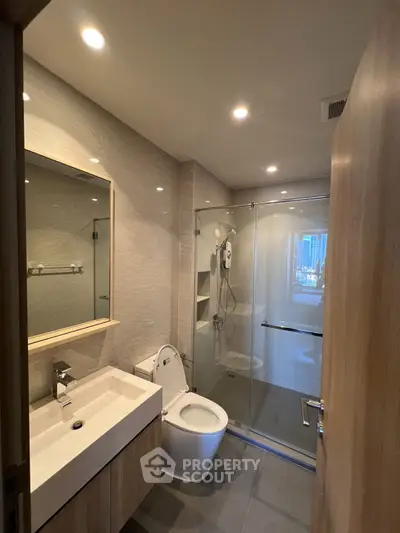 Modern bathroom with glass shower and sleek fixtures in a contemporary apartment.
