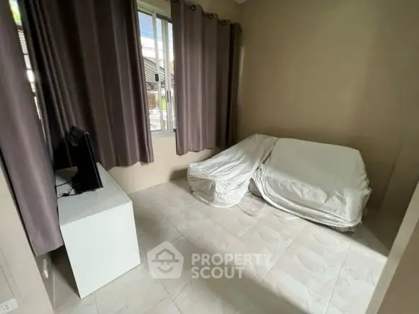 Cozy room with covered furniture and window view, ideal for a study or small living space.