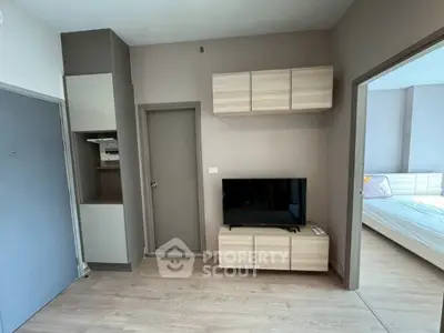 Modern apartment interior with TV unit and bedroom view, showcasing sleek design and functional layout.