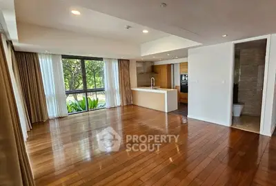 Spacious open-plan living room with hardwood floors and large window view.