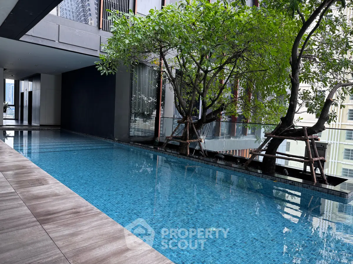 Luxurious modern pool area with serene ambiance and lush greenery in upscale residential building.