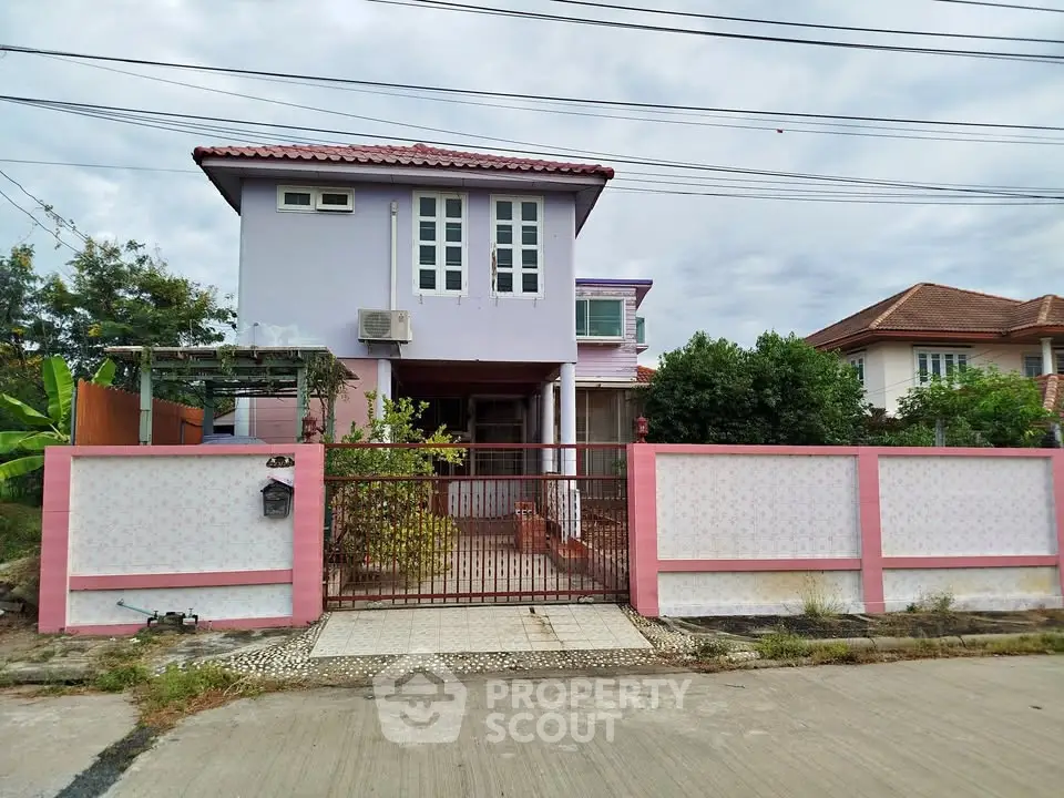 Charming two-story house with pink accents and gated entrance, perfect for family living.