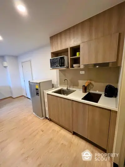 Modern kitchen with wooden cabinetry and appliances in a cozy apartment