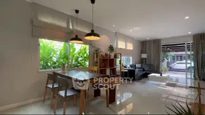 Spacious modern living room with dining area and large windows overlooking greenery.