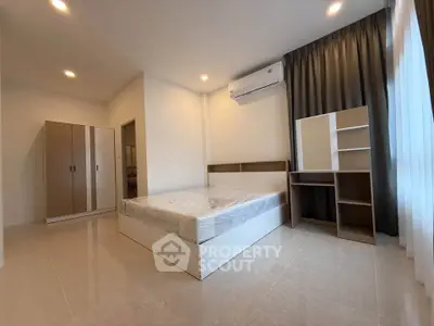 Spacious bedroom with modern furnishings and natural light, featuring a comfortable bed and ample storage.