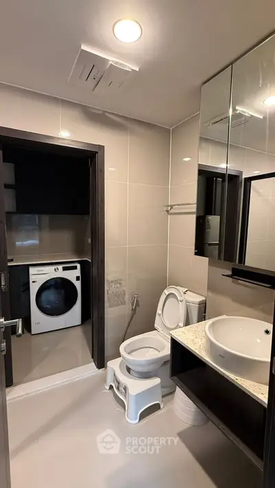 Modern bathroom with washing machine and sleek fixtures in a contemporary apartment.