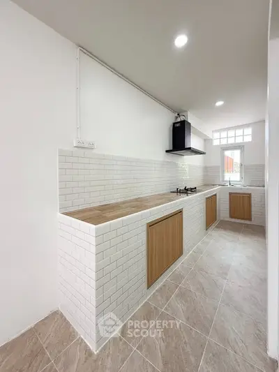 Modern kitchen with white subway tiles and wooden cabinets, featuring a sleek gas stove.