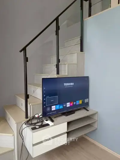 Modern living room with sleek staircase and TV setup, perfect for contemporary urban living.