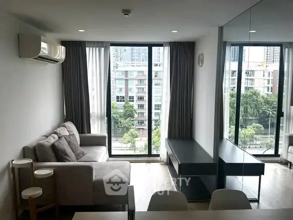 Modern living room with large windows and city view, featuring a cozy sofa and sleek furniture.