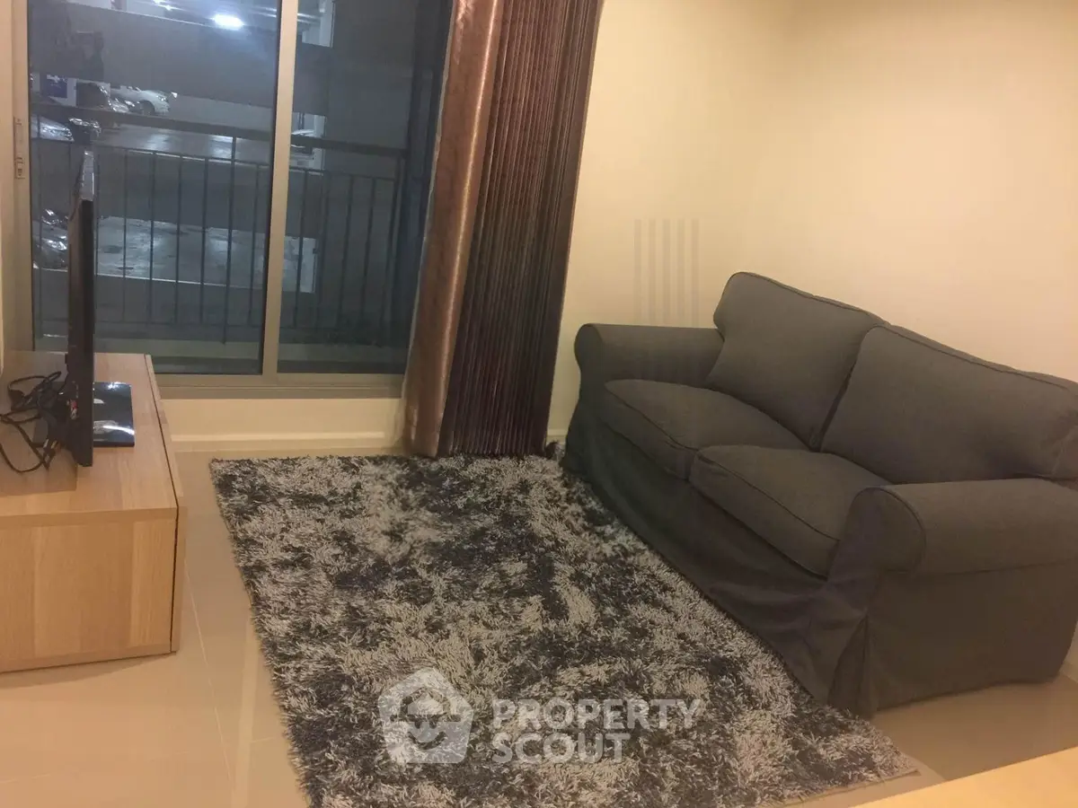Cozy living room with plush gray sofa and modern TV setup, perfect for relaxation.