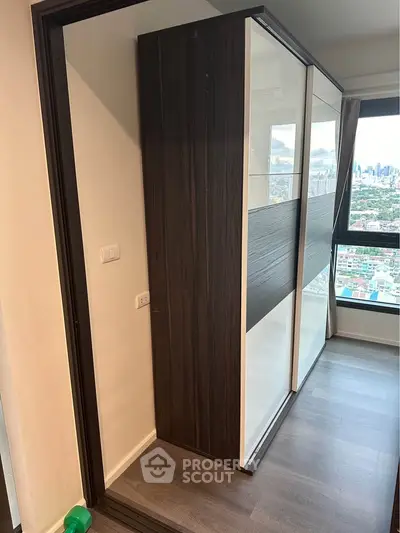Modern apartment interior with sleek sliding wardrobe and city view.