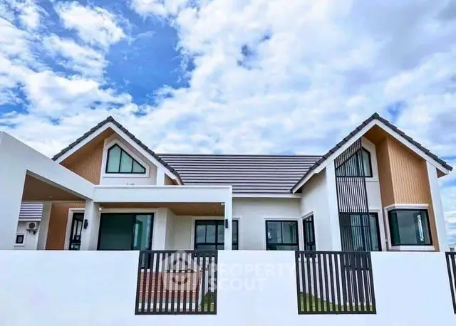 Modern single-story house with stylish roof and large windows under a blue sky.