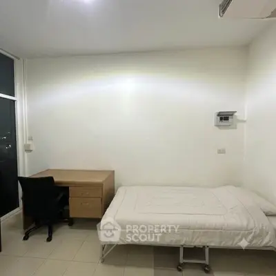 Minimalist bedroom with single bed, desk, and chair, featuring a bright and clean design.