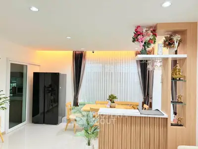 Modern living room with elegant decor and natural light, featuring a stylish dining area and sleek cabinetry.