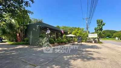 Charming roadside cafe with lush greenery and outdoor seating under a clear blue sky.
