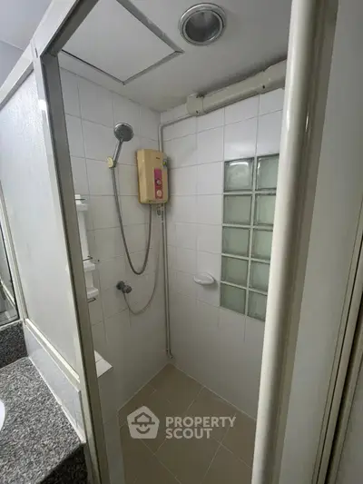 Compact bathroom with shower and tiled walls in modern apartment
