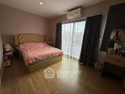 Spacious bedroom with elegant bed, wooden flooring, and large window with curtains.