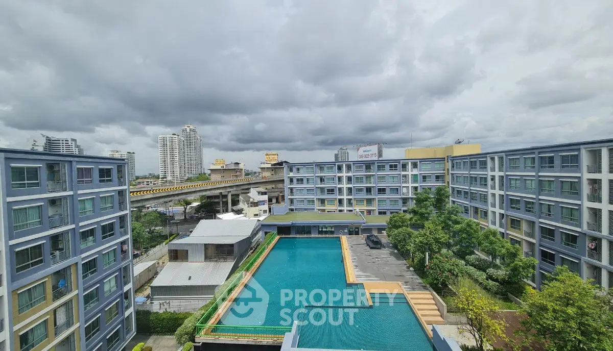 Modern apartment complex with central pool and cityscape view, ideal for urban living.
