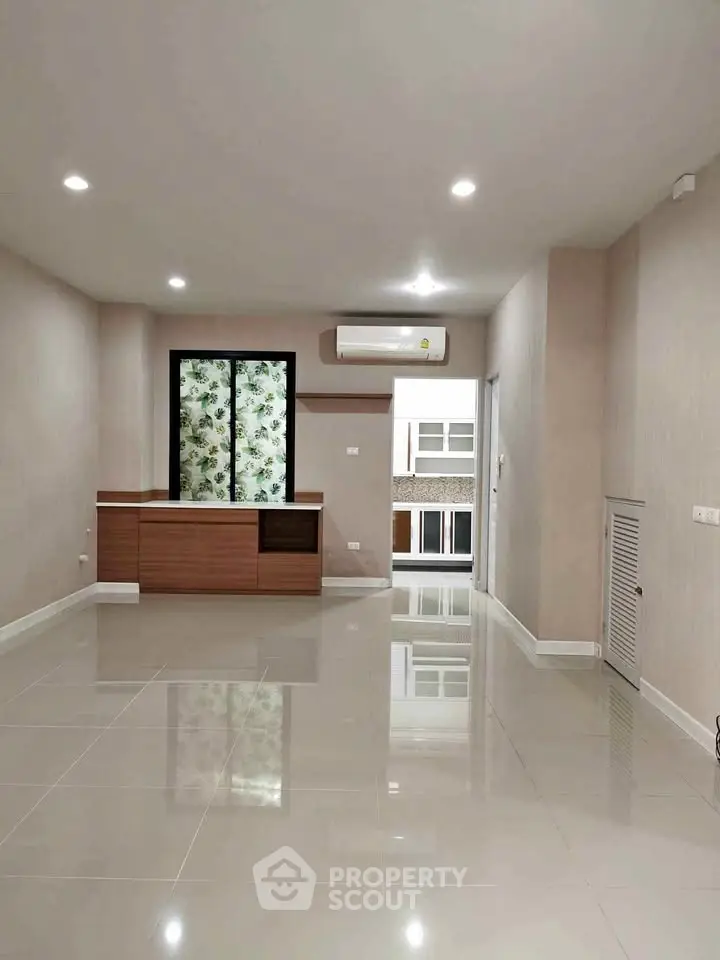 Spacious modern living room with sleek tile flooring and built-in storage unit.