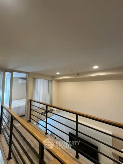 Modern loft-style interior with wooden railing and cozy bedroom view
