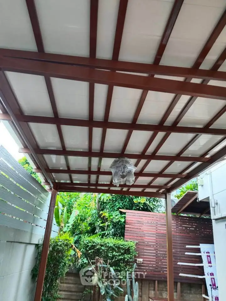 Charming outdoor patio with wooden pergola and lush greenery, perfect for relaxation and entertaining.