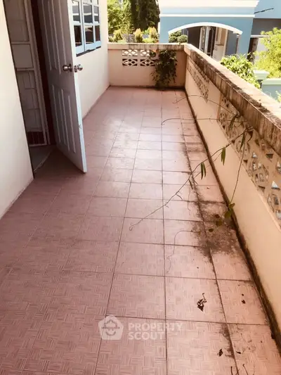Spacious balcony with tiled flooring and partial view of surrounding buildings.